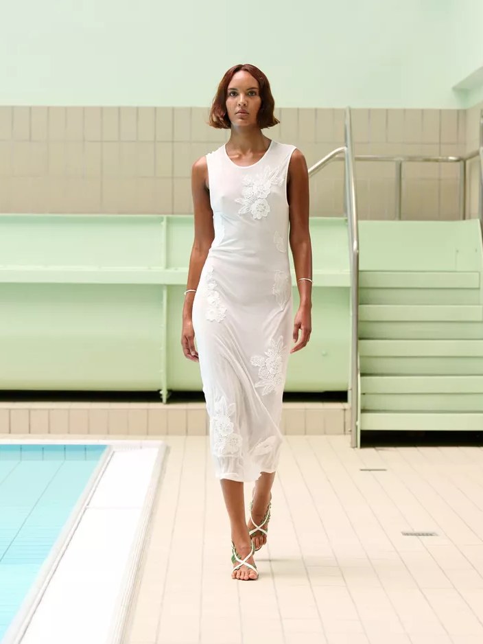 Model in a white embroidered sleeveless dress at the pool runway