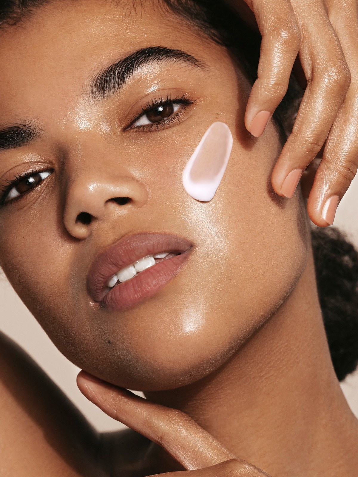 Model with cream on her cheek in warm studio light