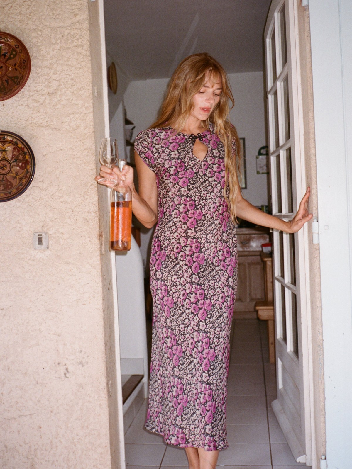 Model wearing a printed Ciao Lucia dress in a Mediterranean-style doorway