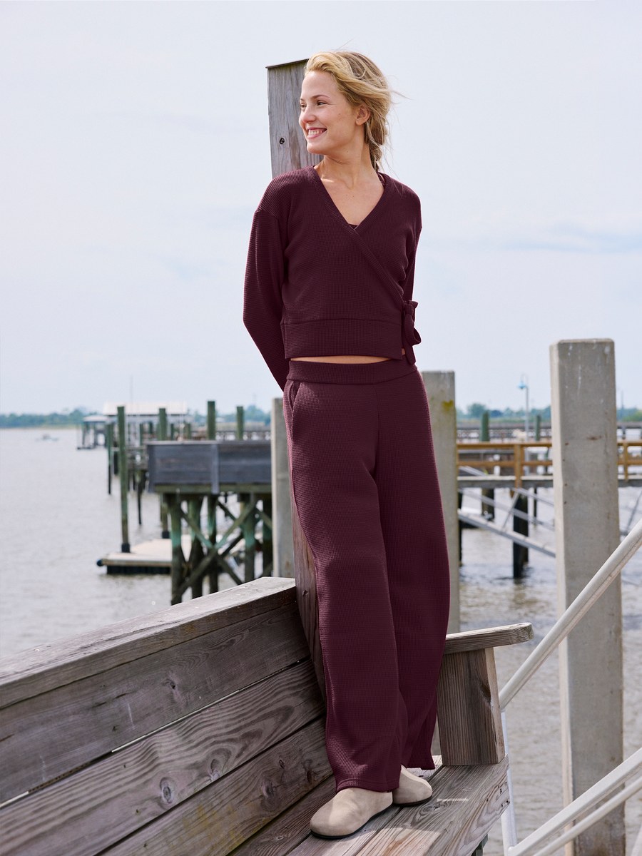 Woman in a burgundy set standing by a waterfront pier