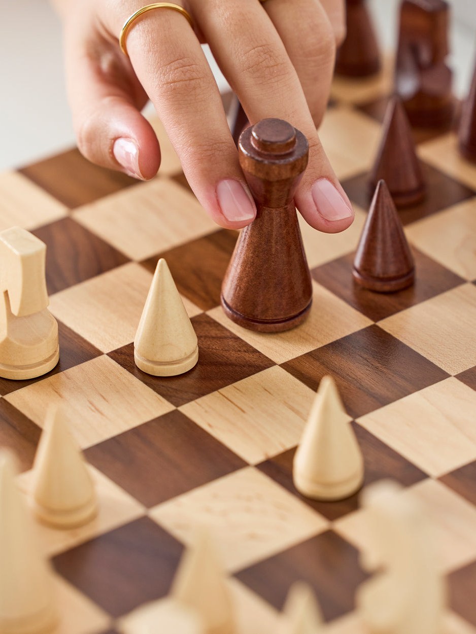Close-up of a hand moving a chess piece on a two-tone board