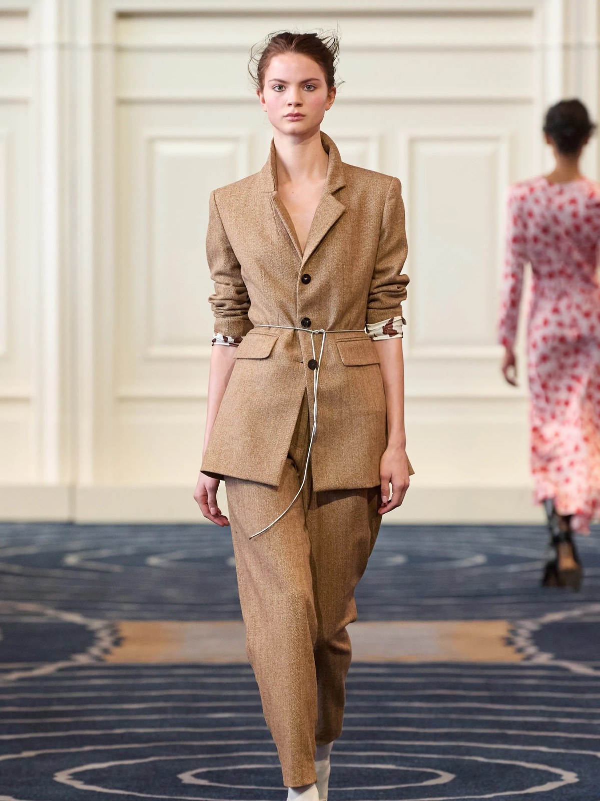 Model in a belted tan suit on the Alejandra Alonso Rojas runway