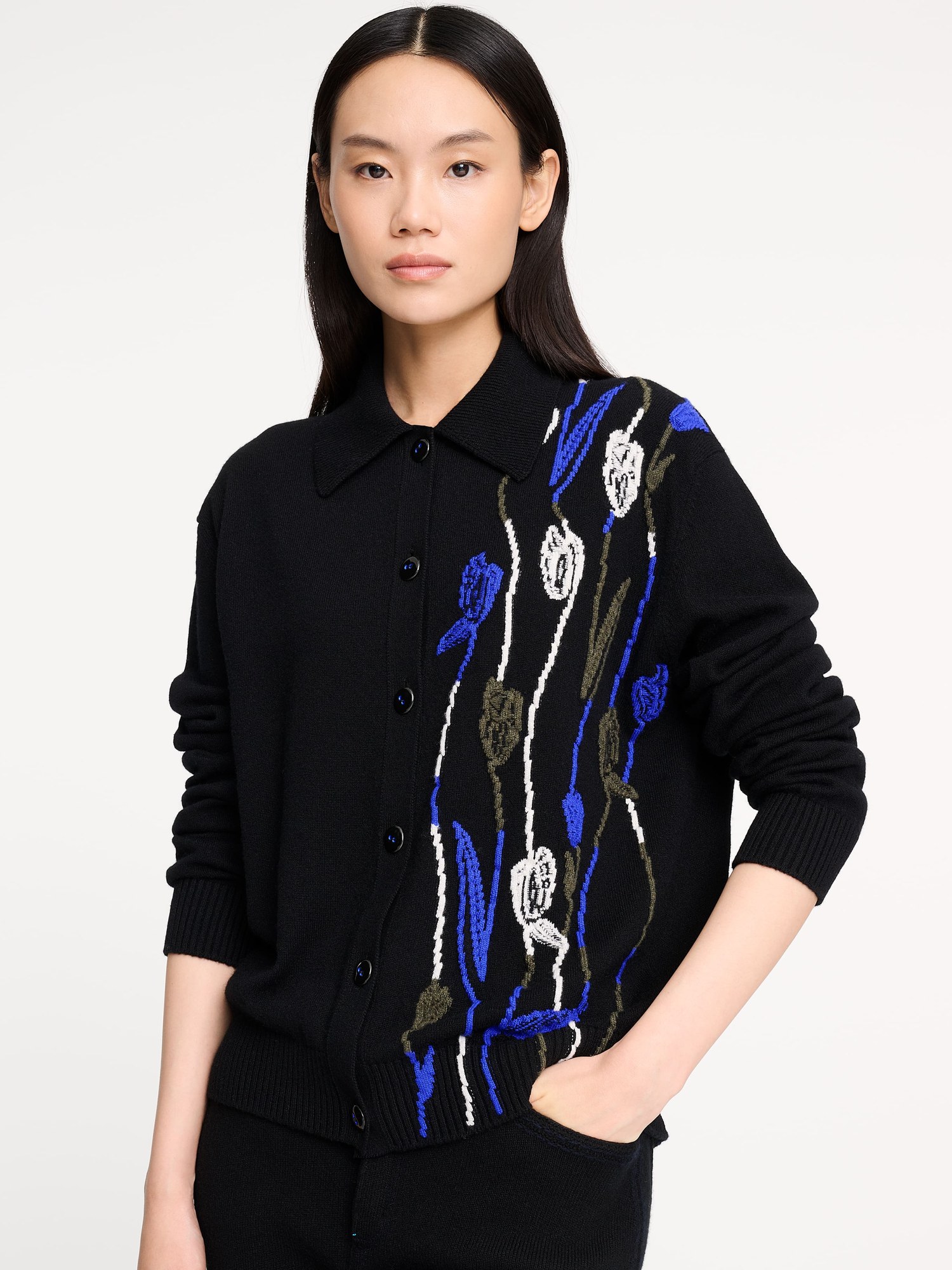 Model in a black cashmere polo cardigan with a blue and white tulip motif