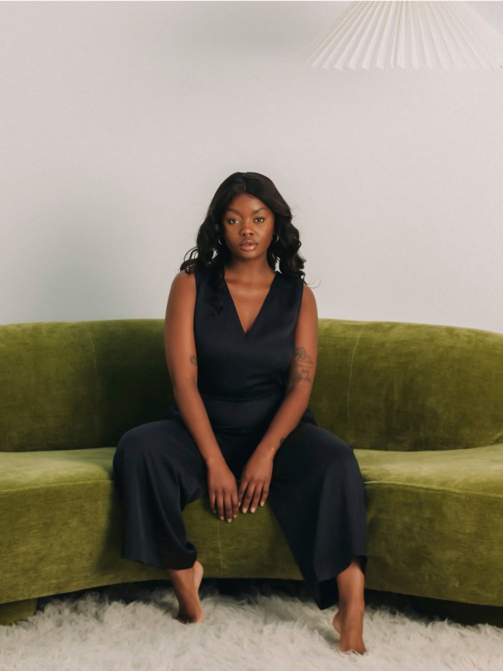Woman seated on a sculptural green sofa in a styled room