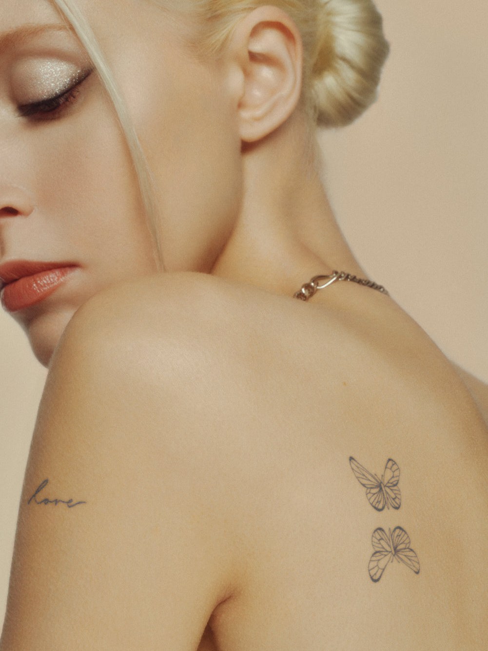 Model with fine-line temporary butterfly tattoos on her shoulder