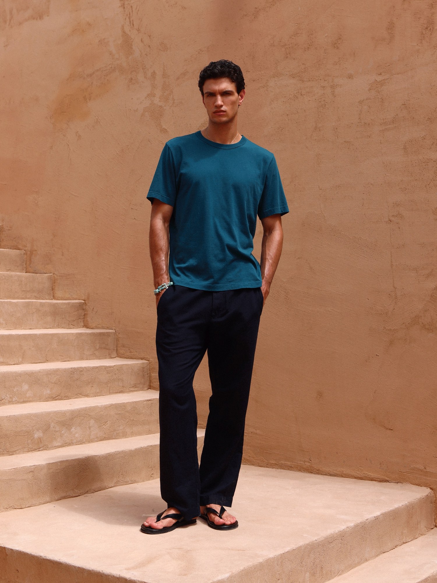Man in a teal tee and black pants on terracotta stairs