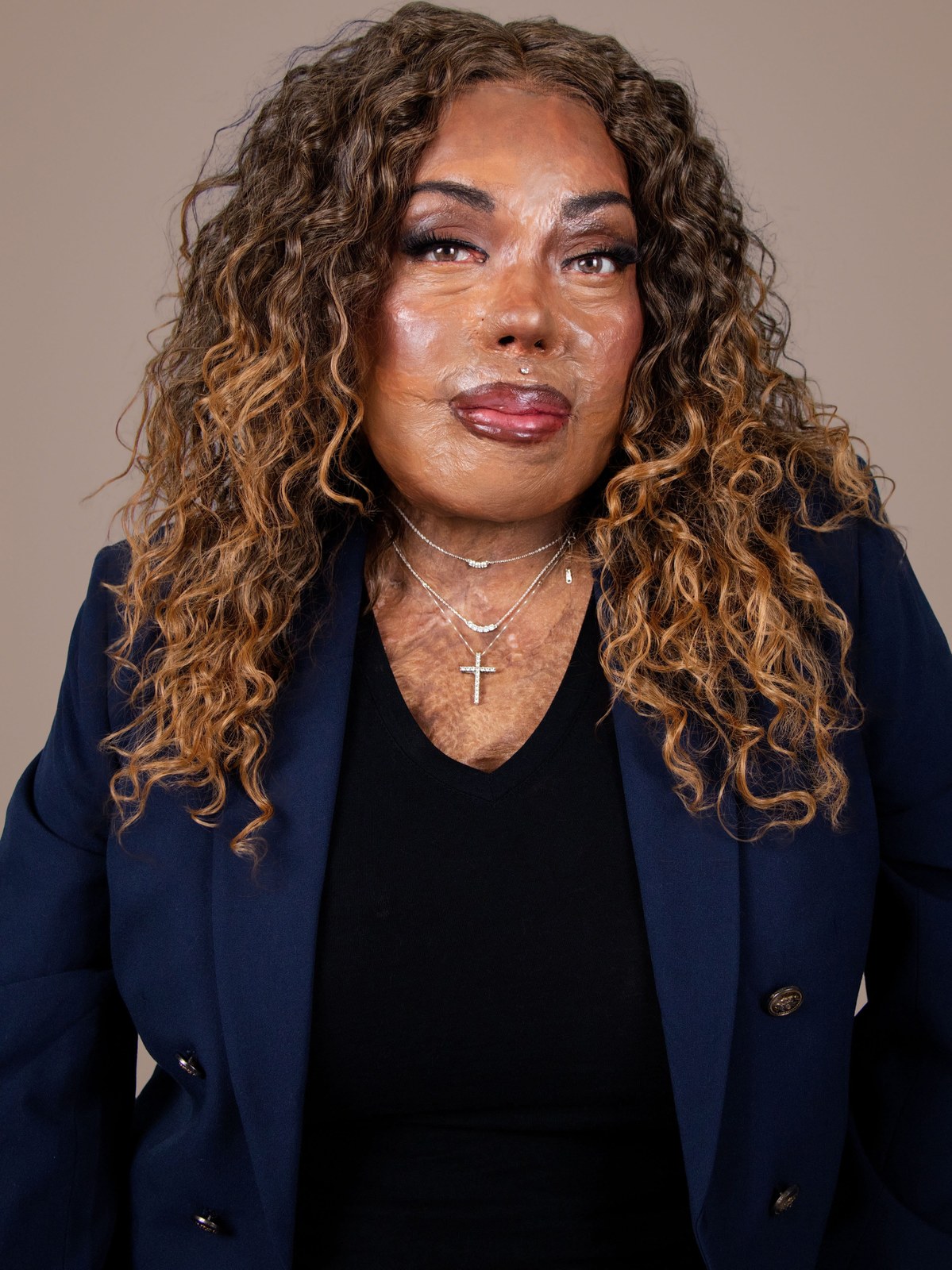 A woman in a navy blazer against a pale studio backdrop