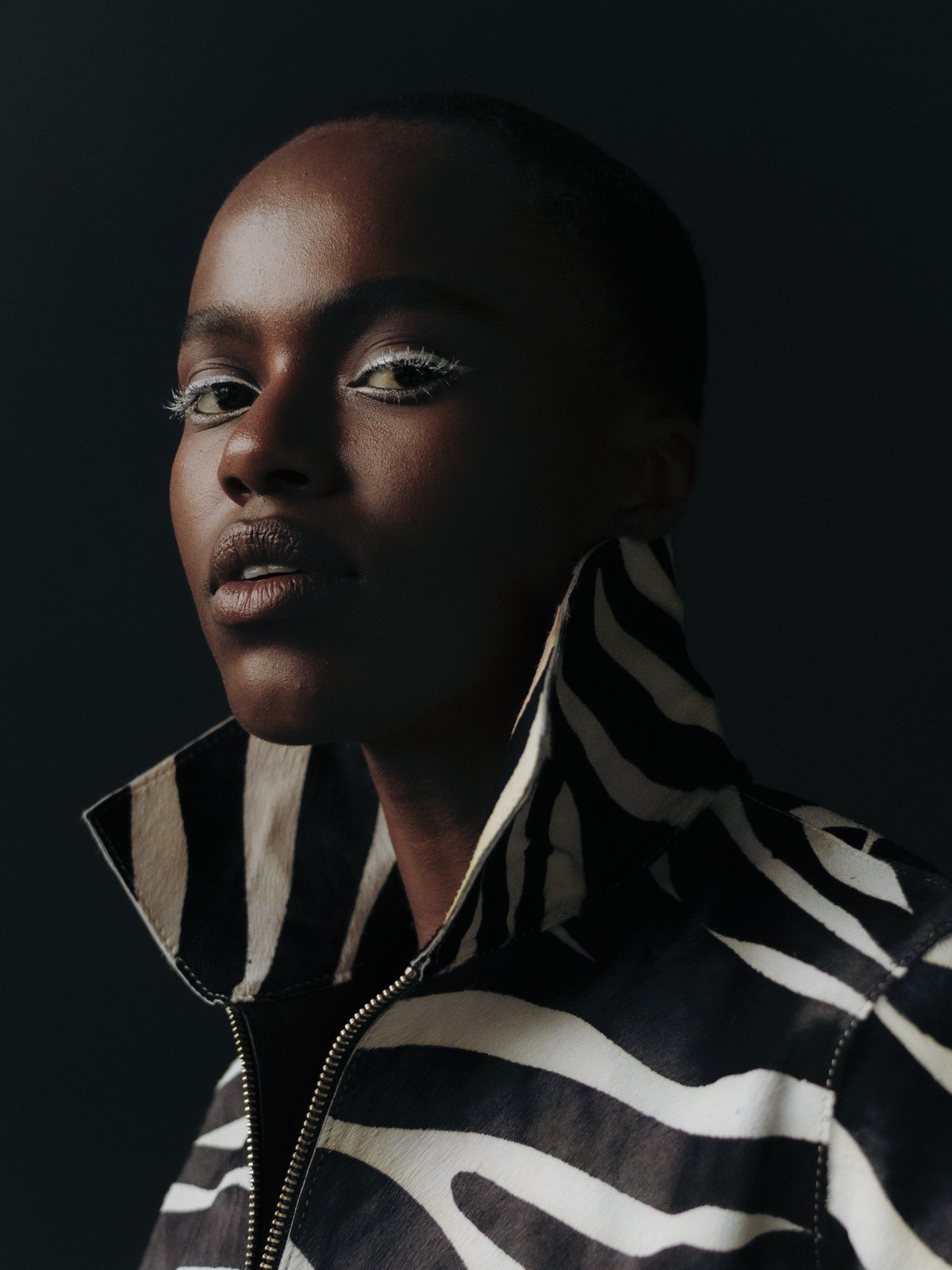 Model in a black and white striped jacket against a dark background