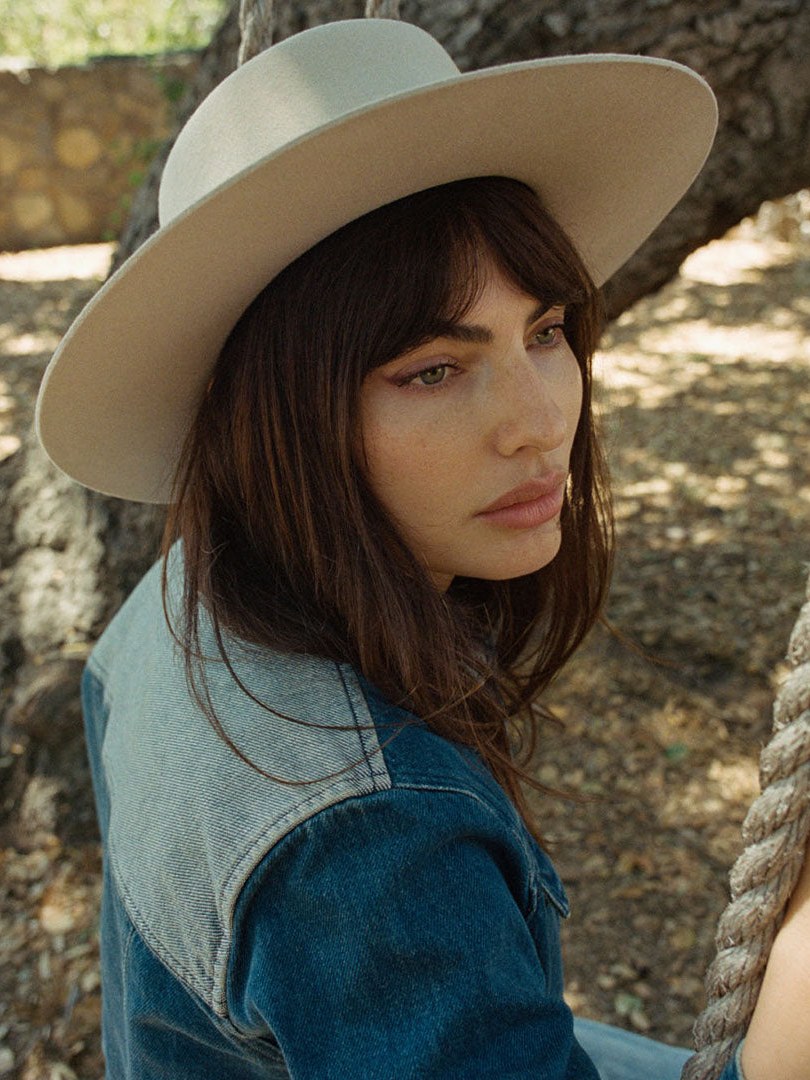 Woman in a wide brim hat and denim jacket outdoors