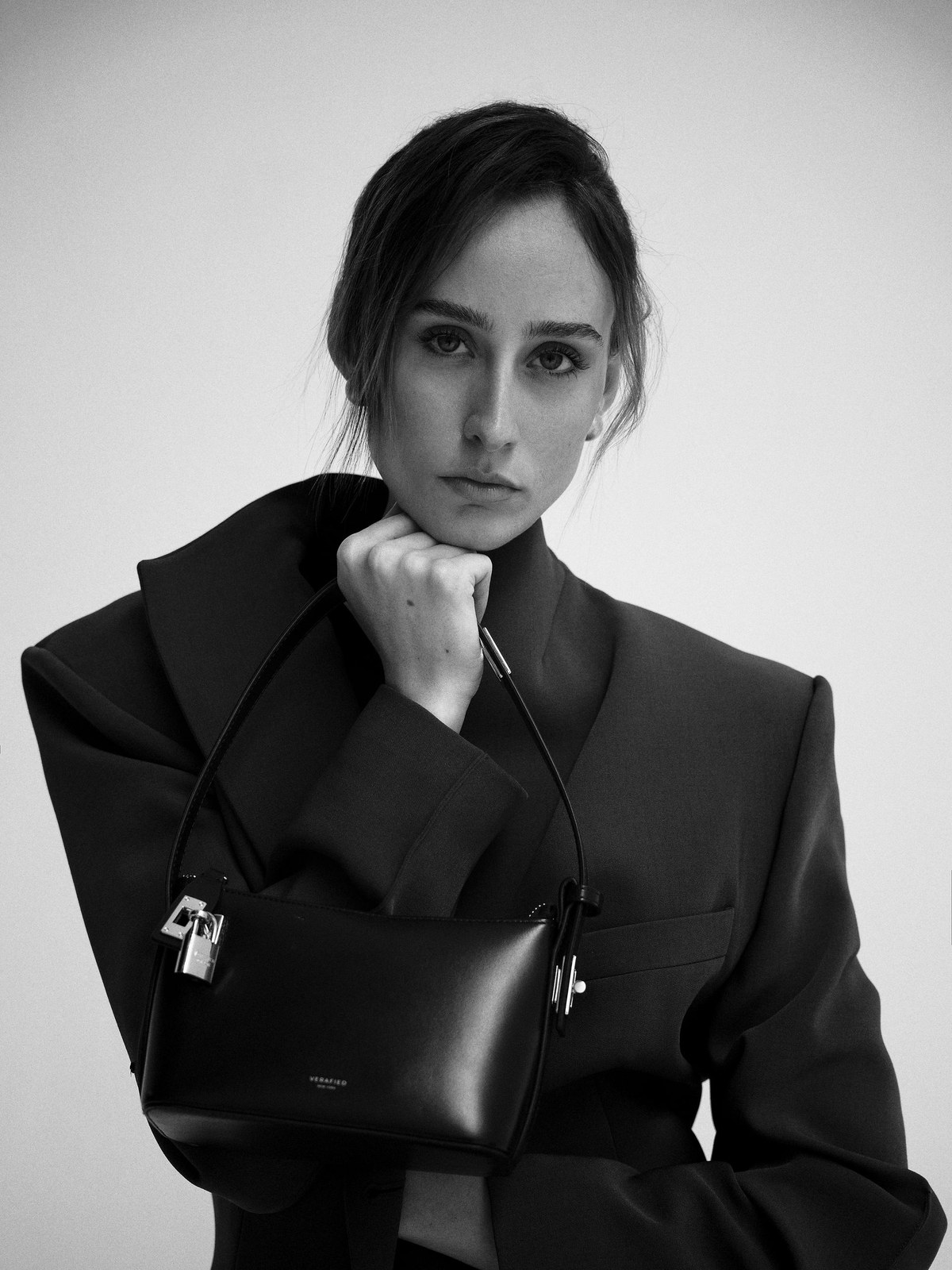 Black and white campaign portrait of a model carrying a VERAFIED shoulder bag