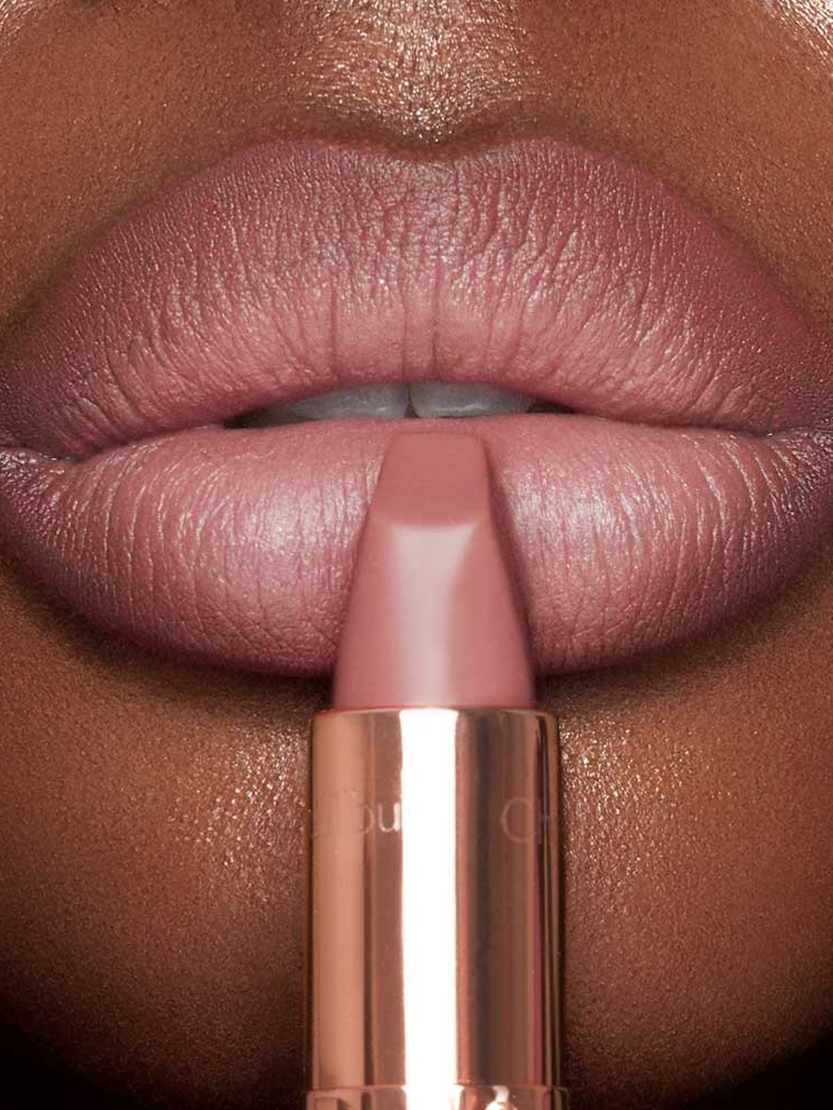 Deep skin tone lips with a Pillow Talk lipstick held at the mouth