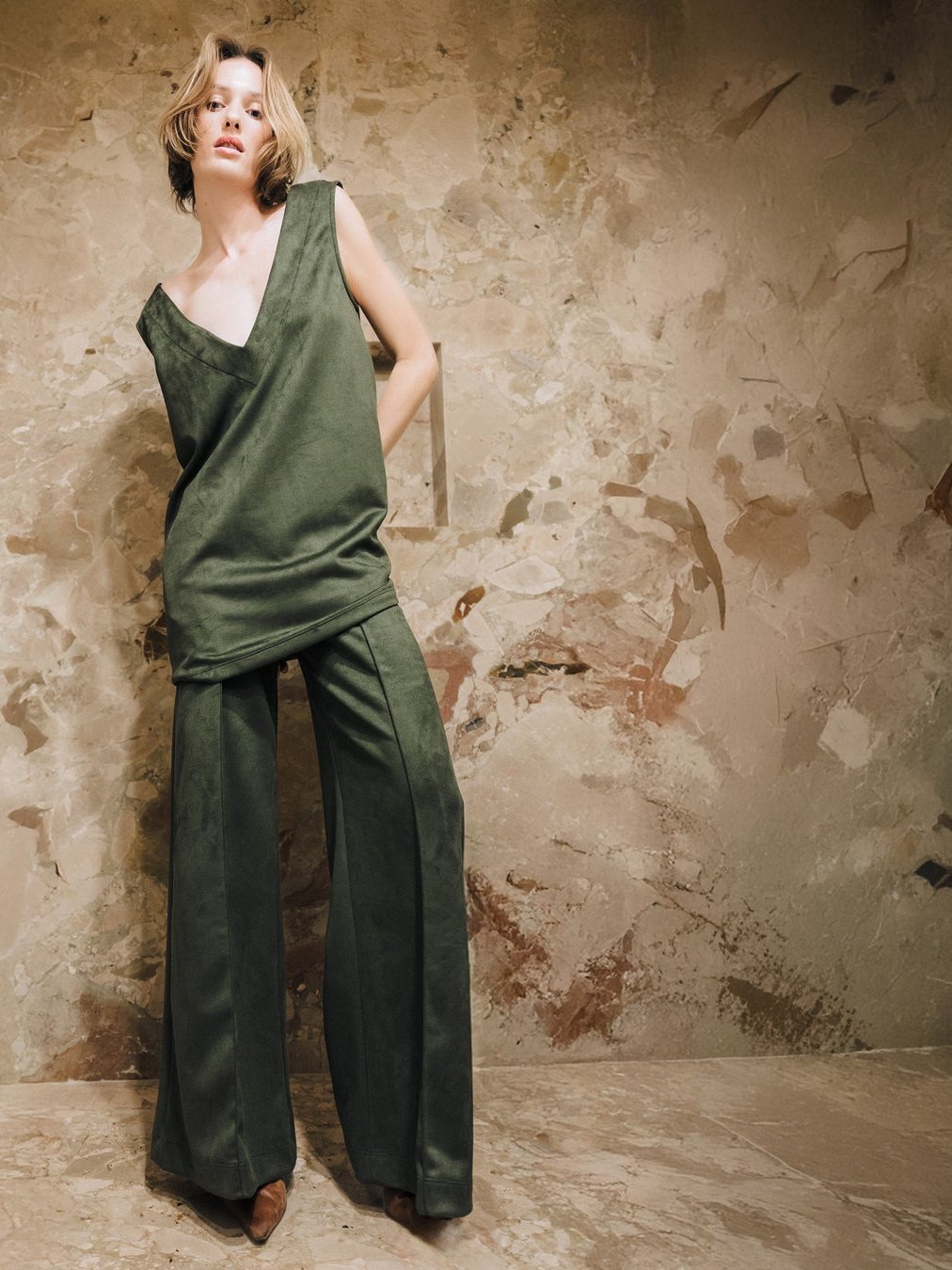 Model in an olive Ripley Rader set against a textured studio wall