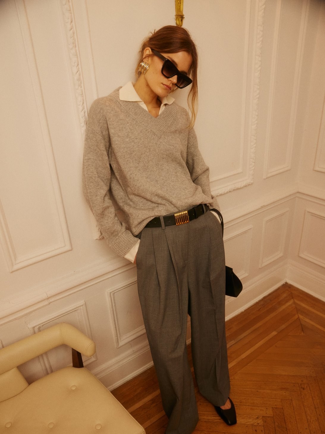 Model in a grey knit and tailored trousers indoors.