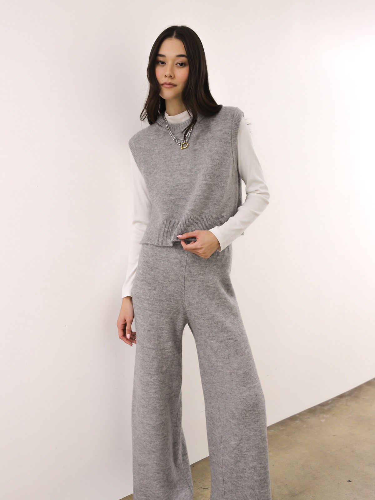 Model in a grey knit vest and trousers in a studio