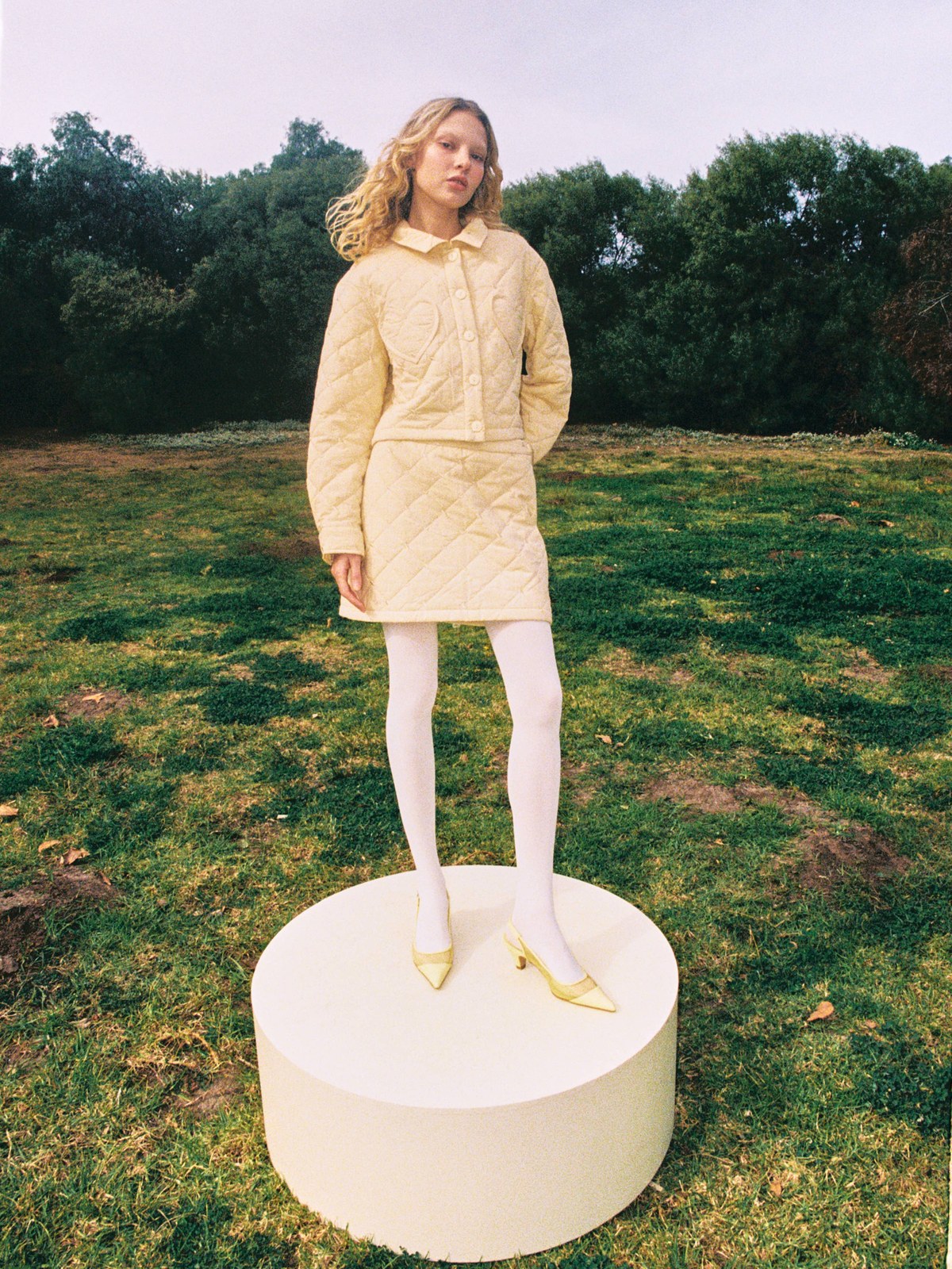 Woman wearing a pale yellow quilted Lisa Says Gah outfit in a garden