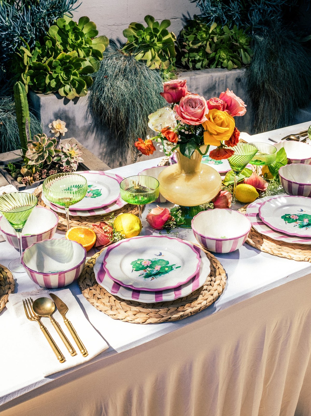 Colorful floral plates and green glasses arranged for an outdoor meal
