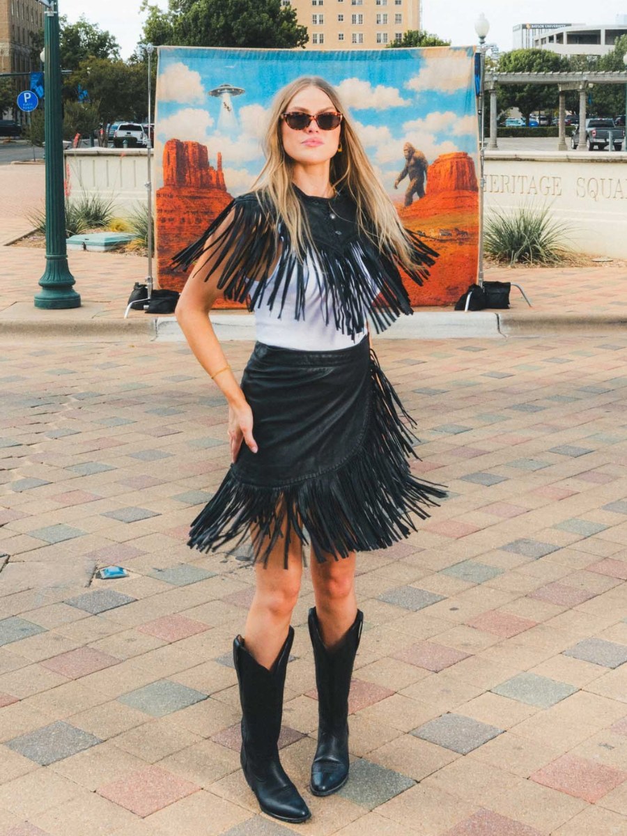 Woman in a black fringe outfit on a city square with a desert backdrop