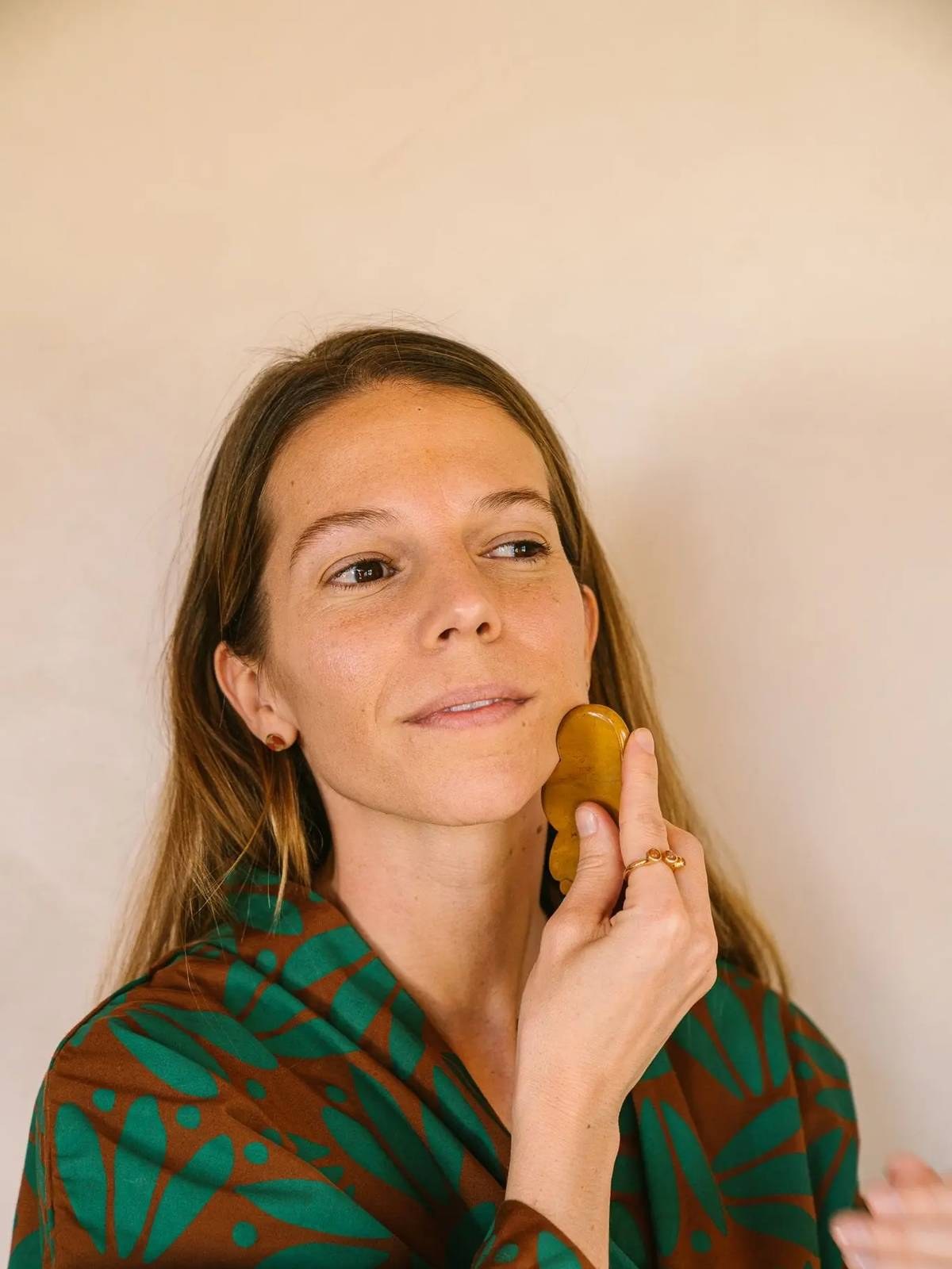 Woman applying a gua sha tool to her cheek