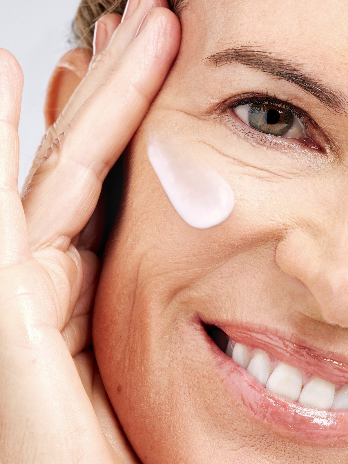Close-up of a model applying skincare beside her eye