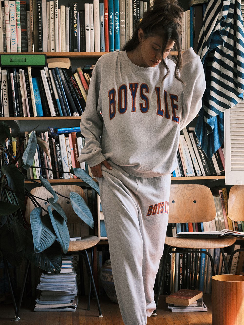 Model in a gray graphic sweatsuit among bookshelves