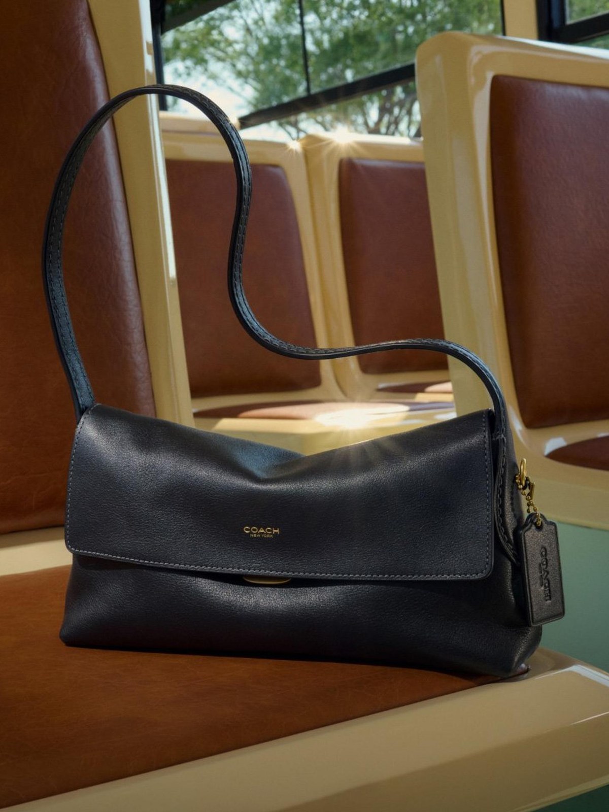 Black leather shoulder bag on a cream and tan subway seat