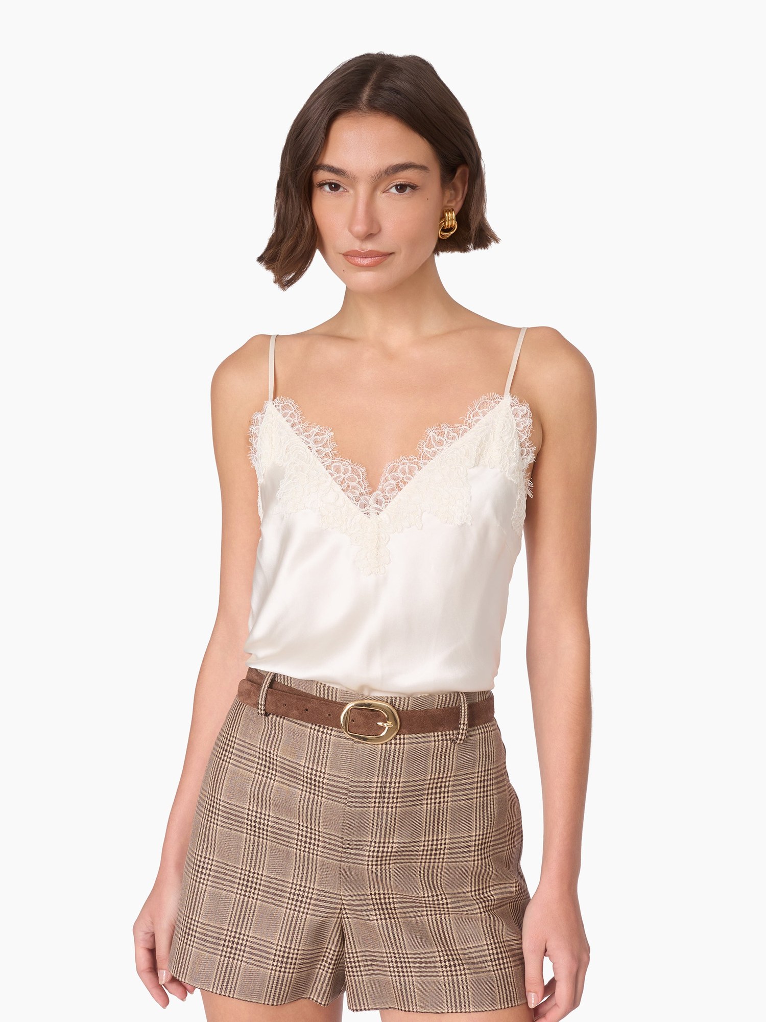 Model with a bob in an ivory lace trim cami and plaid shorts with a belt