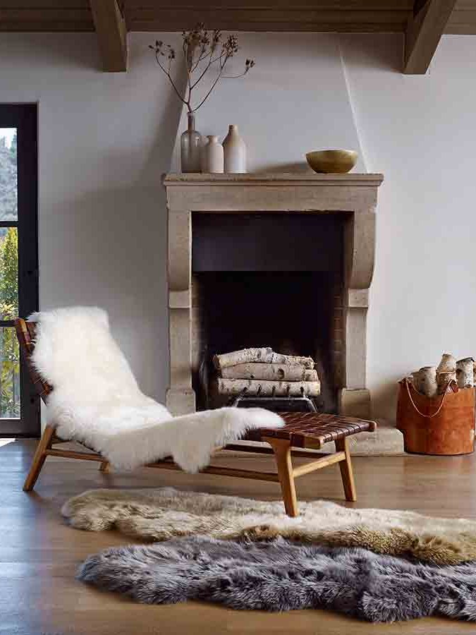 Soft throw on a wooden chaise beside a fireplace