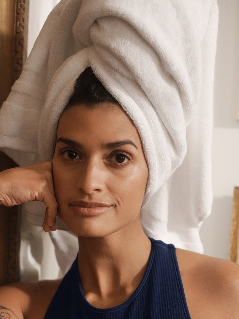 Model with a white towel wrapped around her hair wearing a navy ribbed bra top