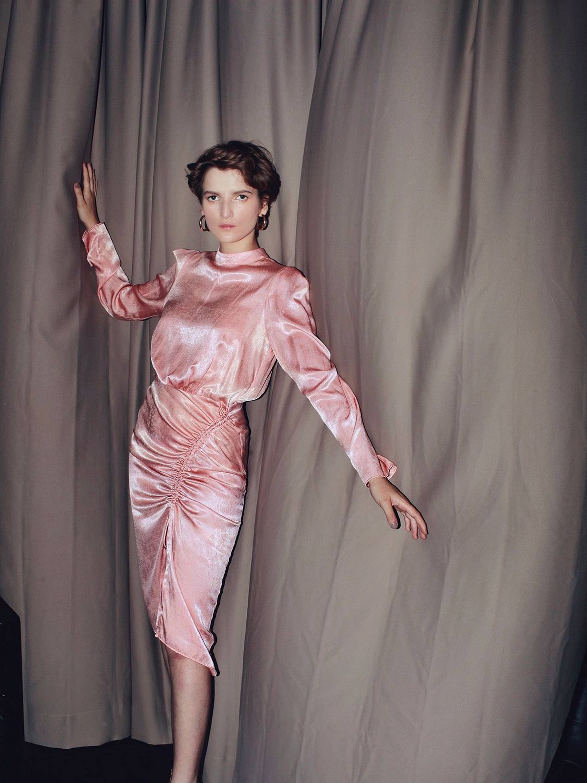 Model in a pink satin look against draped fabric