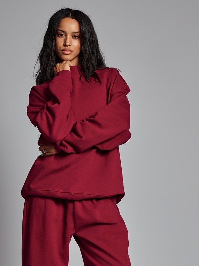 Model in a burgundy sweatshirt and matching pants in a studio