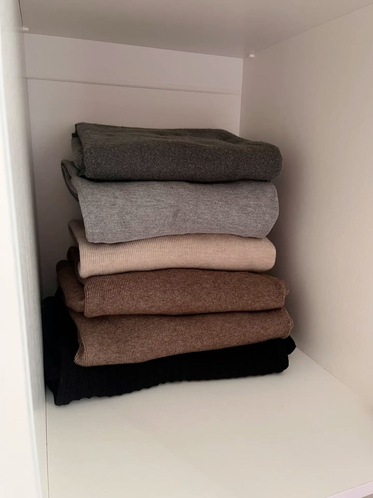 Soft sweaters stacked in a white cupboard