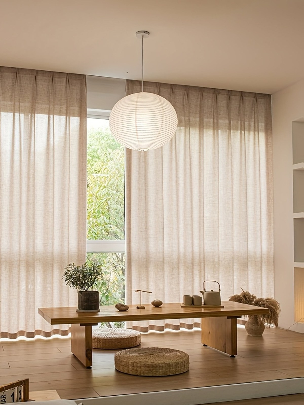 Dining nook with sheer curtains and a paper pendant light
