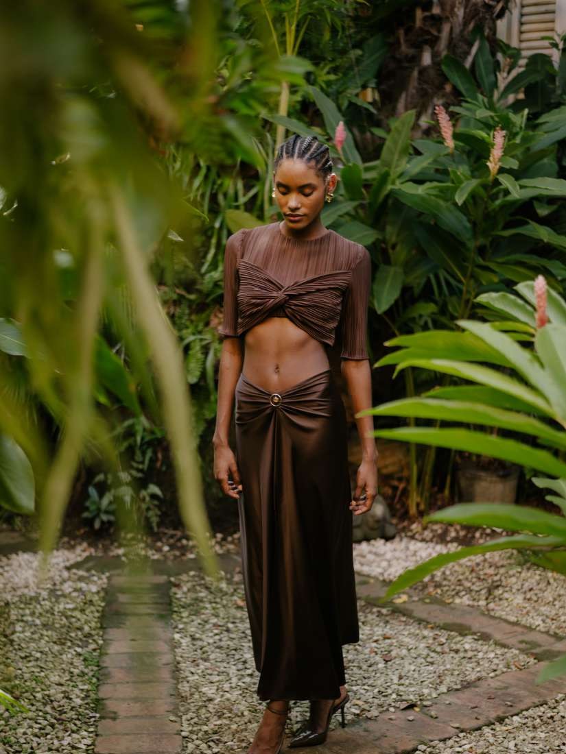 Model in a brown two-piece look in a tropical garden