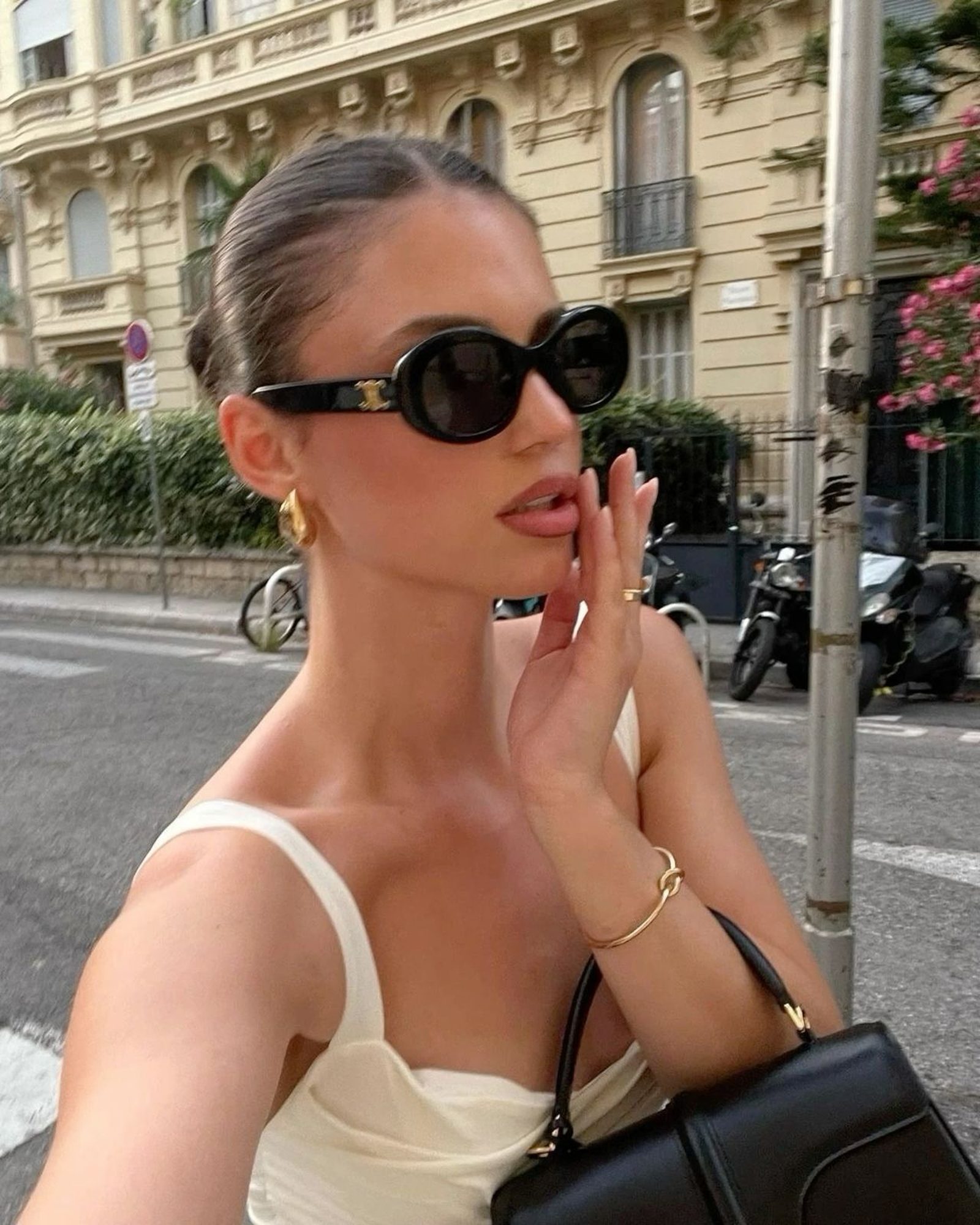 Woman in a cream tank top with black CC sunglasses and a black bag on a Paris street