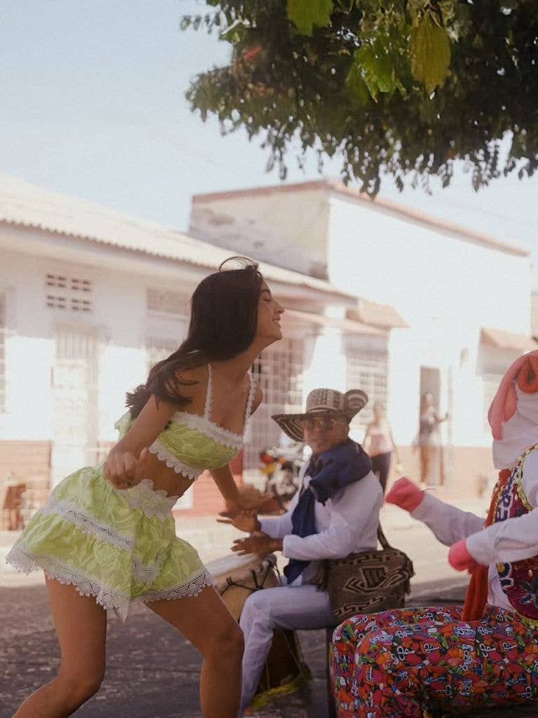 Model in a lime set dancing with musicians in Colombia.