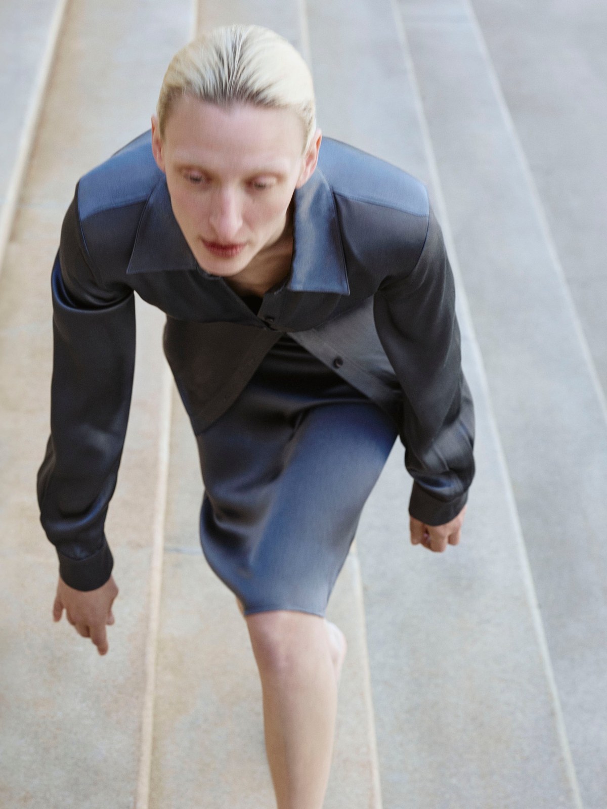 Model in a blue-gray leather outfit on stone steps