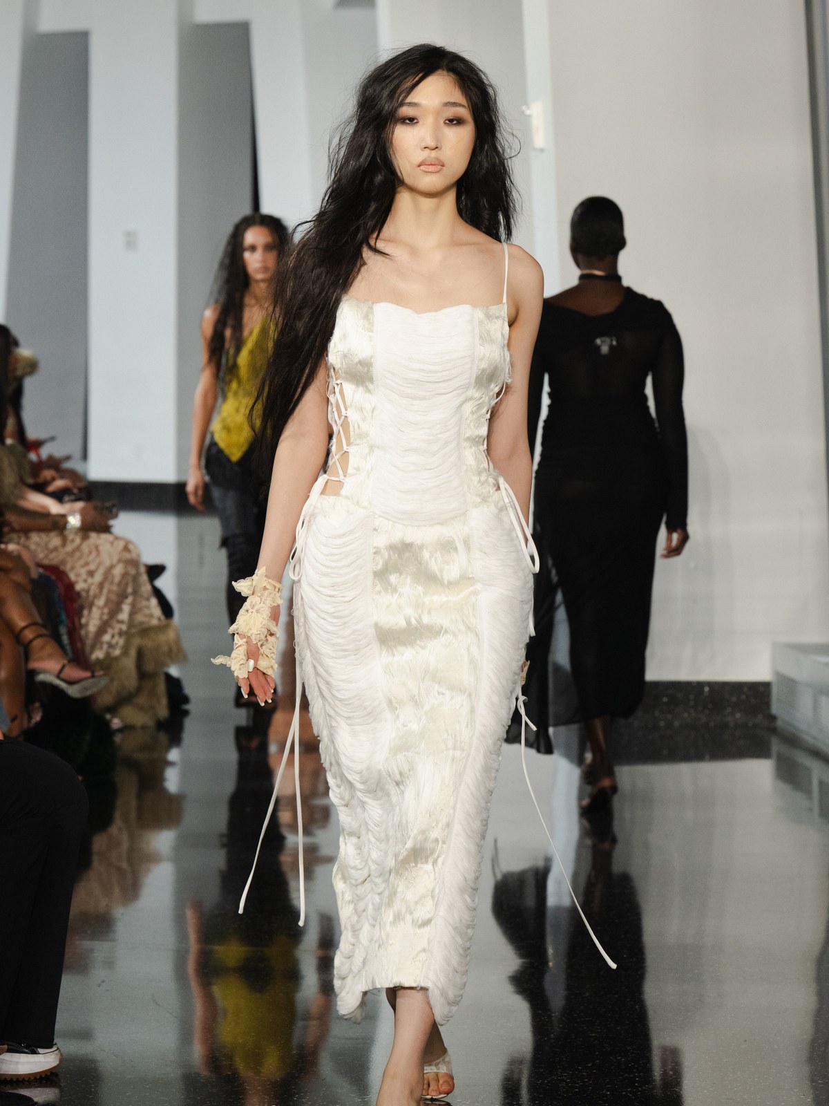 Model in a white lace dress walking on the runway
