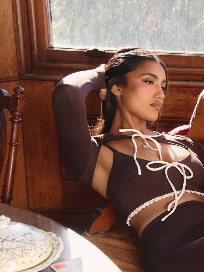 Woman lounging on a velvet sofa in a dark activewear set