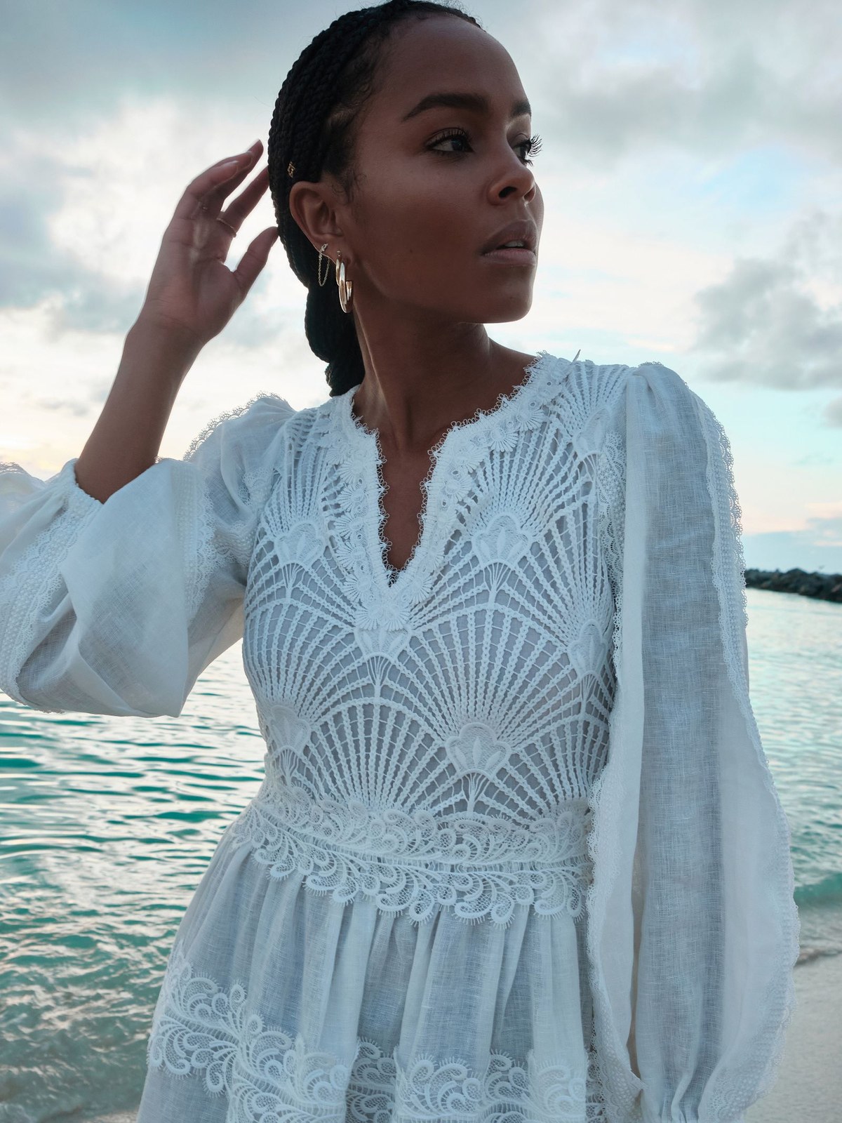Model in a white lace blouse beside the sea.