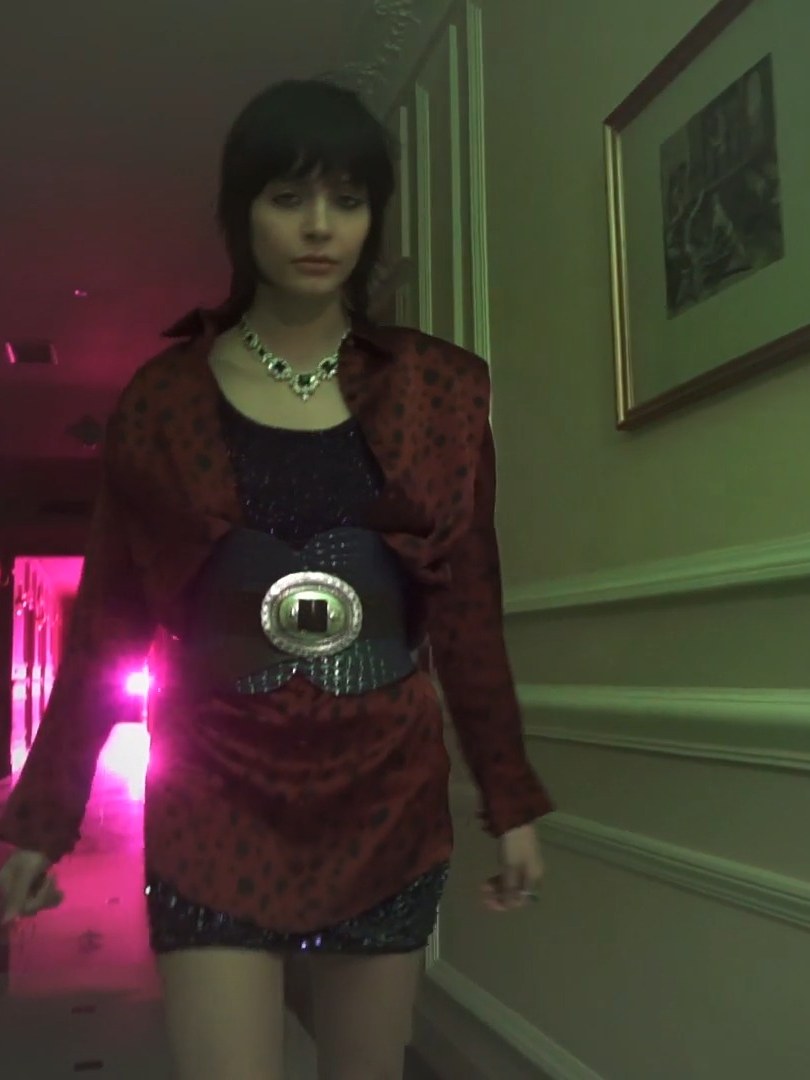 Woman in a red patterned jacket and mini dress walking through a hotel
