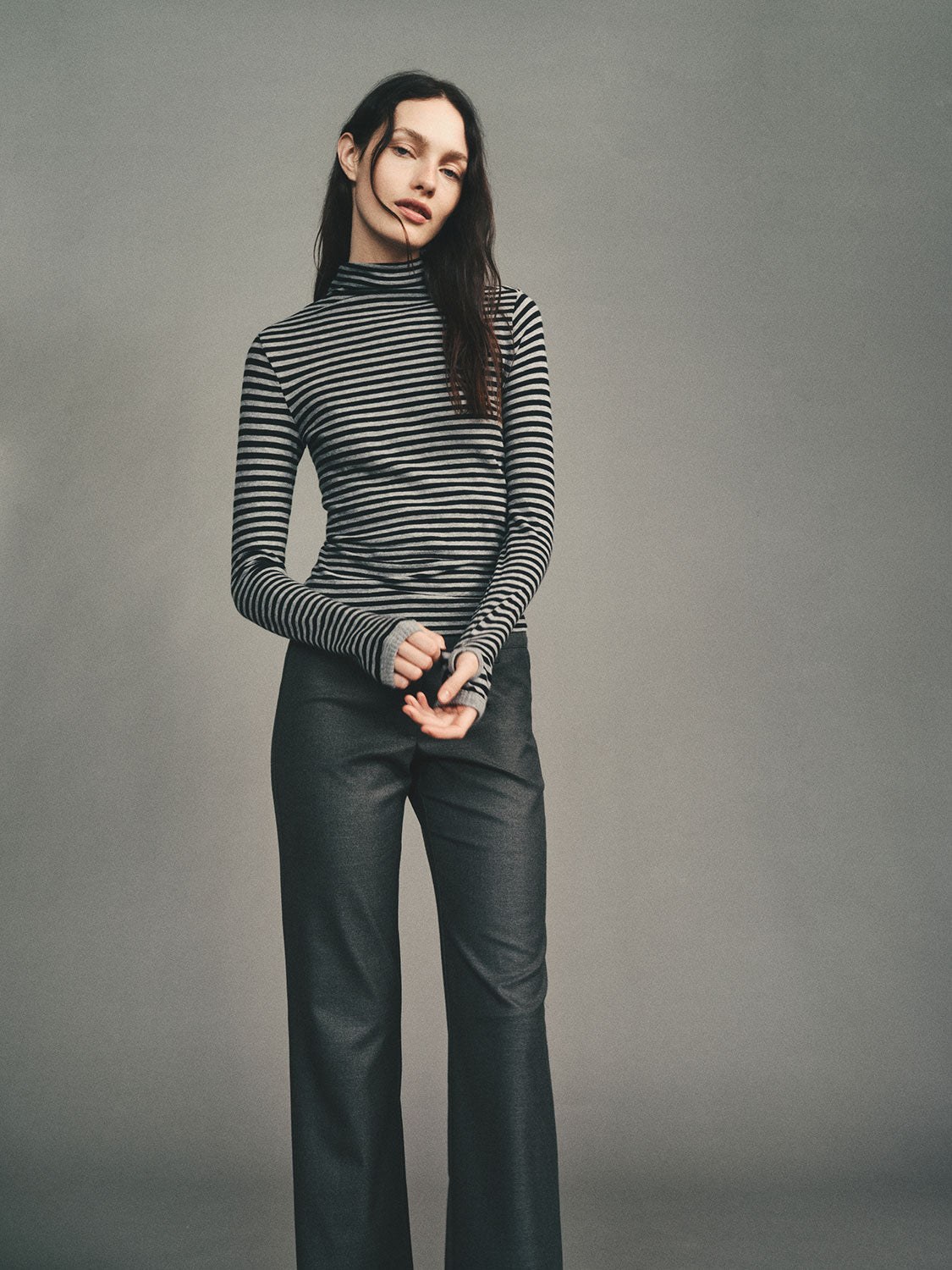 Model in a striped long sleeve and dark trousers in a studio