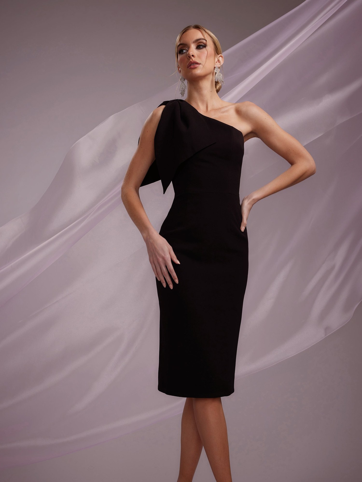 Model in a black one shoulder cocktail dress against sheer fabric