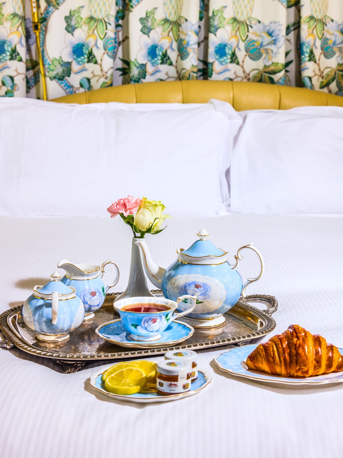 Blue floral tea service arranged on a breakfast tray beside a croissant