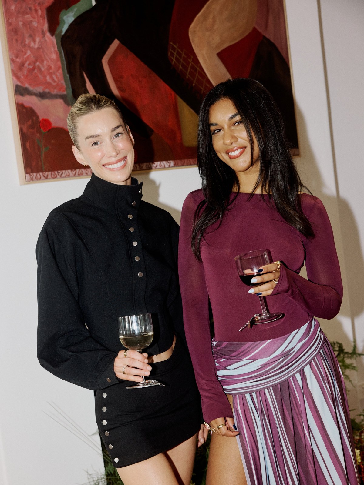 Two women in black and burgundy separates at an art event