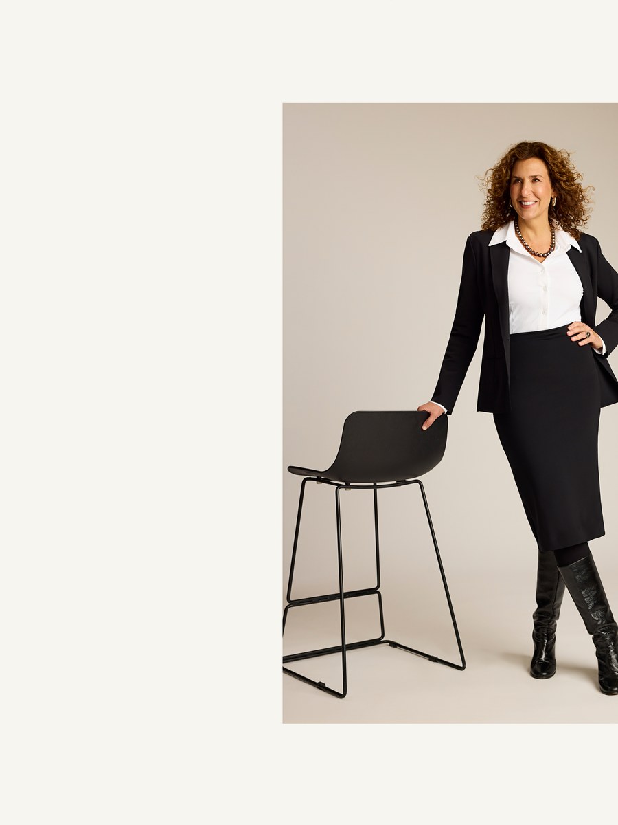 Commando founder Kerry O’Brien in a black blazer and skirt beside a chair