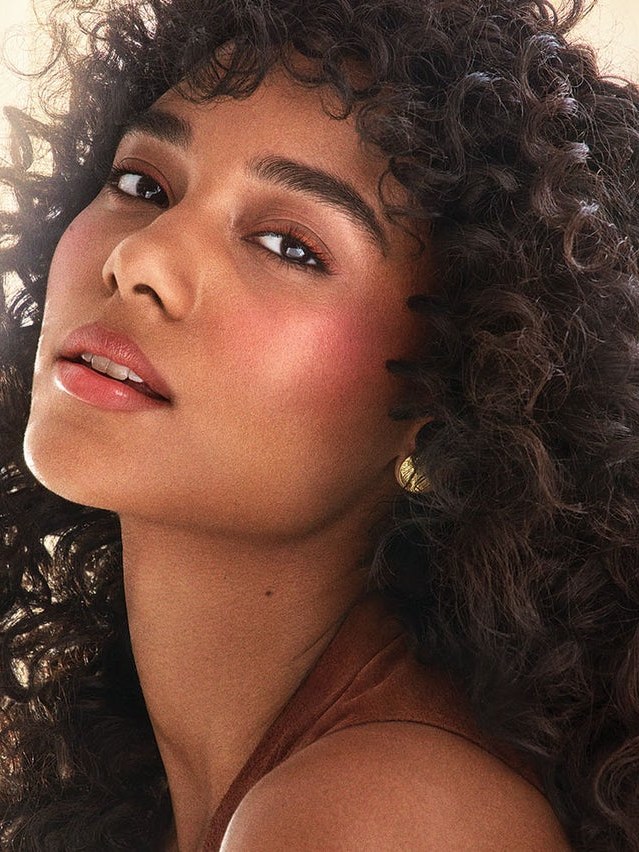 Model with rose blush and natural curls from a Stila collaboration campaign