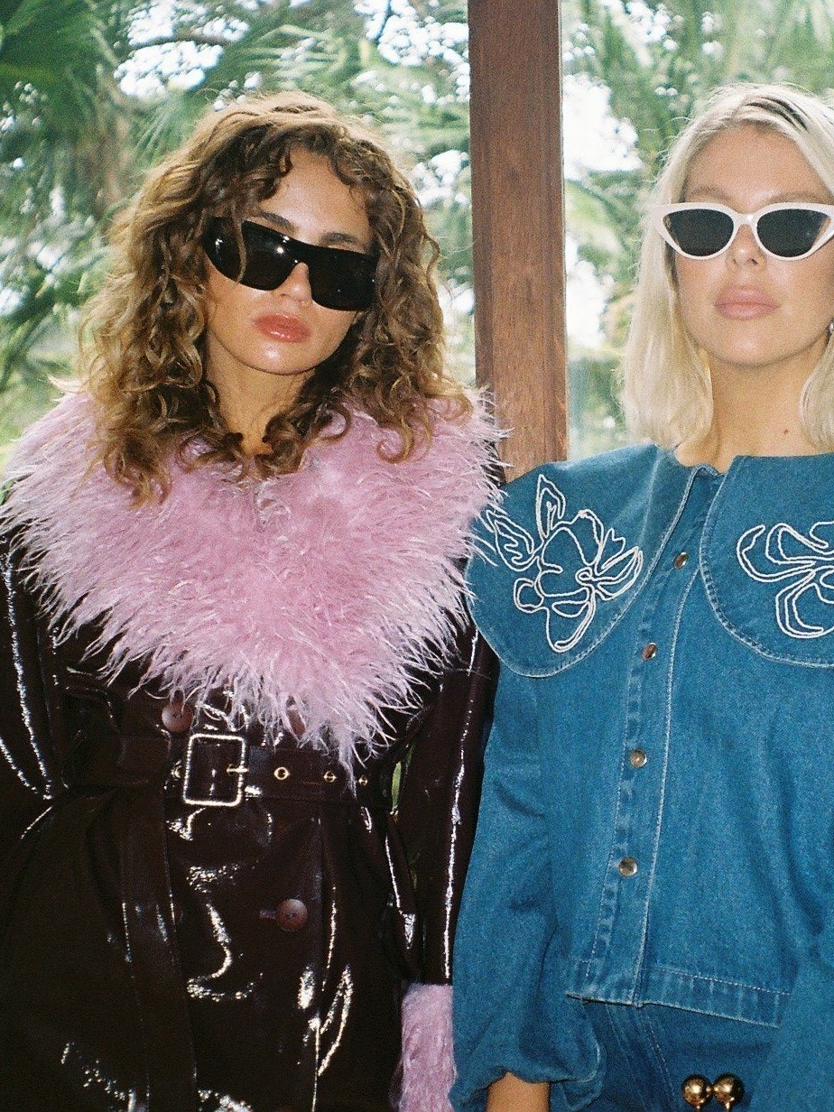 Two women in colorful textured layers under tropical palms