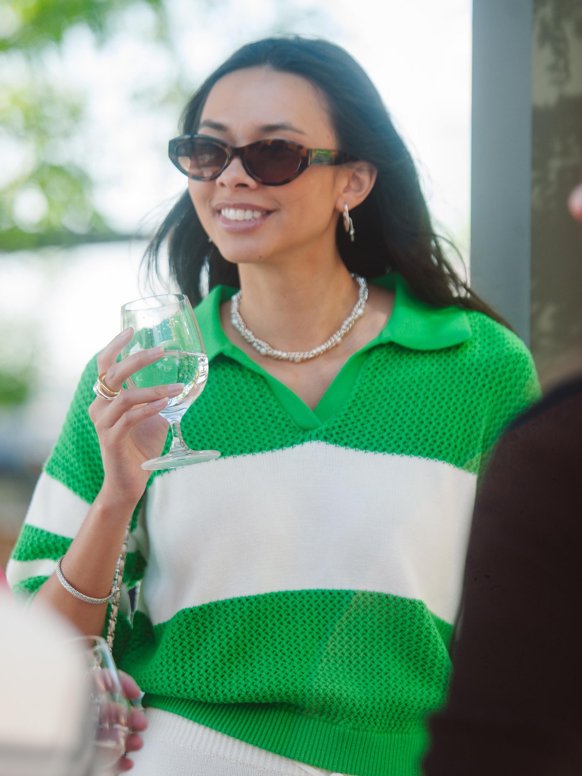 Guest in a green and white knit top at a 525 America summer gathering