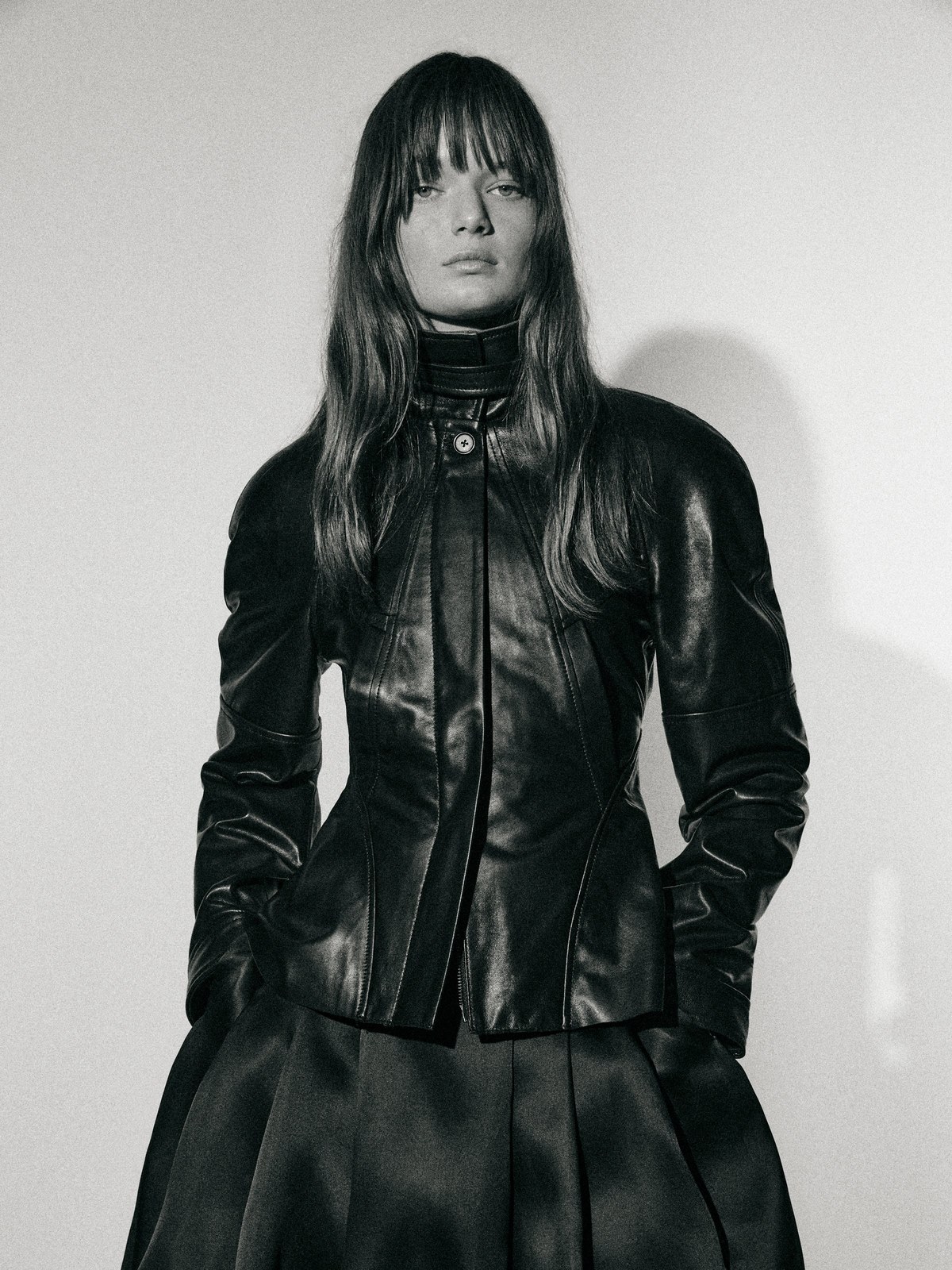 Model in a black leather jacket and dark skirt in a monochrome studio