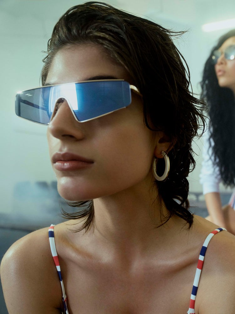 Woman wearing a blue mirrored shield frame and a striped swimsuit